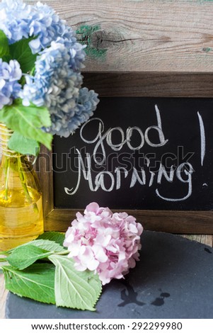 Blue and pink hydrangea in a vase with good morning note on the blackboard