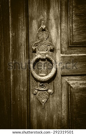 Castle gate doorknocker. Aged photo. Vignette. Sepia.