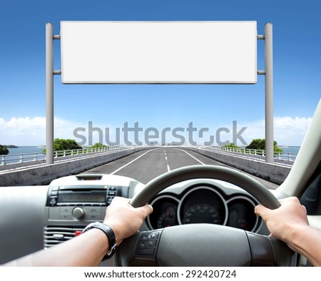 Man driving a car while looking at billboard or road sign ahead