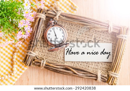 Have a nice day card and pocket watch at 6 AM with flower on wooden background.