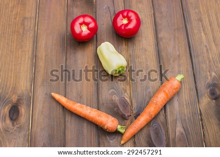 smiling face lined with fresh vegetables on a wooden background in the garden