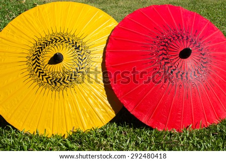 Colorful umbrellas on grass field ; Bo-sang umbrella handicraft made from paper of Chiang Mai, Thailand. 