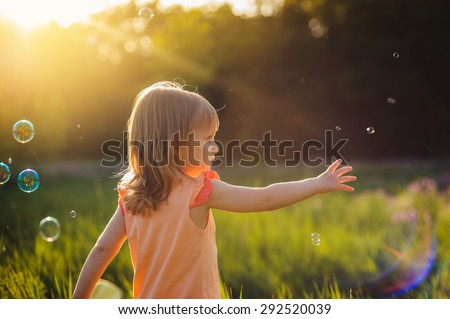 The little girl among bubbles at sunset