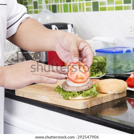 Chef putting slice of tomato on the Hamburger bun /Cooking Hamburger concept