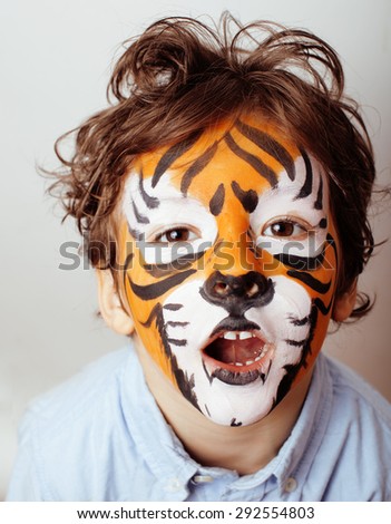 little cute boy with faceart on birthday party close up, orange tiger