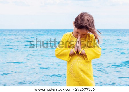 Little funny beautiful girl does yoga on the beach. Selective focus.