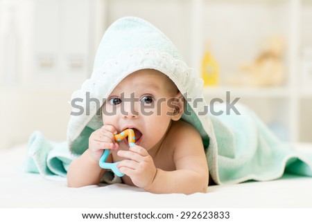 baby with teether in mouth under bathing towel at nursery Royalty-Free Stock Photo #292623833