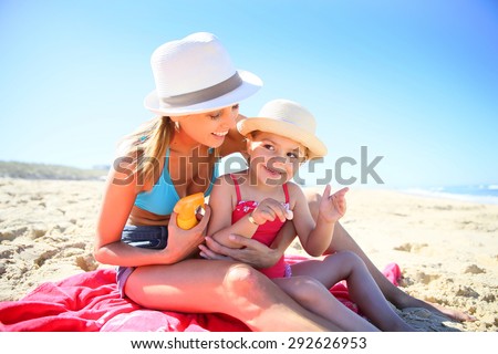 Woman applying sunscreen on daughter's body