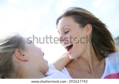 Portrait of young mother holding little girl in arms