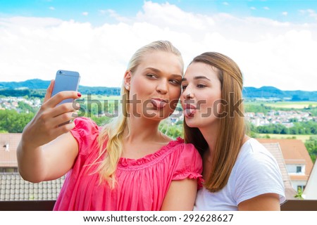 Two girls sticking tongue out and making a self portrait