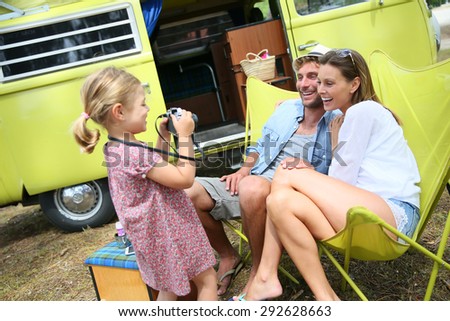 Little girl taking picture of her parents on campground