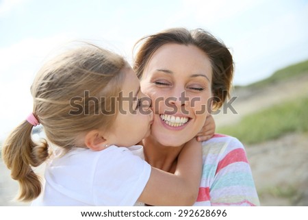 Portrait of cute little girl kissing her mom