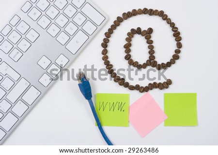 e-mail symbol  made from coffee beans with computer keyboard and sticky notesand a blue network cable