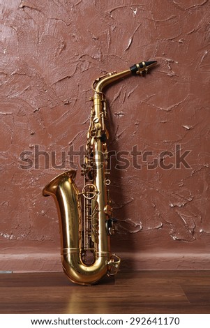 Golden saxophone on brown wall background