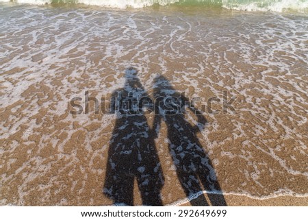 Shadow Of Happy Couple Taking Photos On Beach