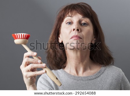 beautiful mature woman displaying dish brush as a house punishment for such a proud lady Royalty-Free Stock Photo #292654088