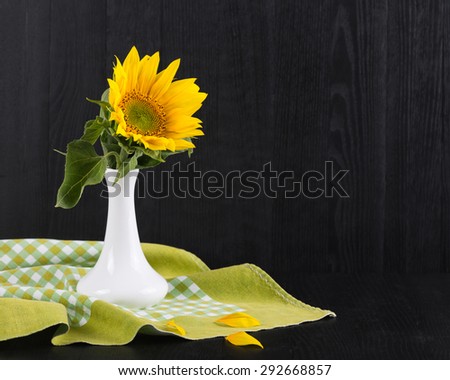 sunflowers in a vase on a black wooden background