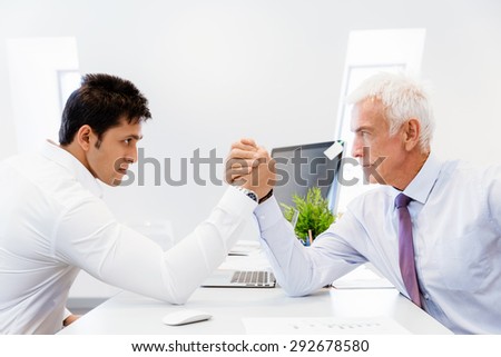 Two businessmen competeting arm wrestling in office