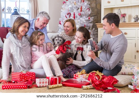 Dad takes a picture of Three Generation Family at Christmas Time. They all look excited about their new Puppy. 