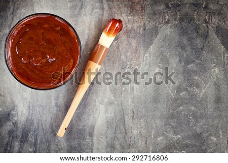 Barbecue sauce with basting brush over stone table with room for copy space. 