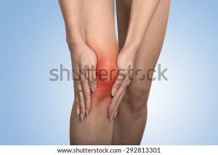 Closeup tendon knee joint problems on woman leg indicated with red spot isolated on blue background. Joint inflammation concept. Royalty-Free Stock Photo #292813301