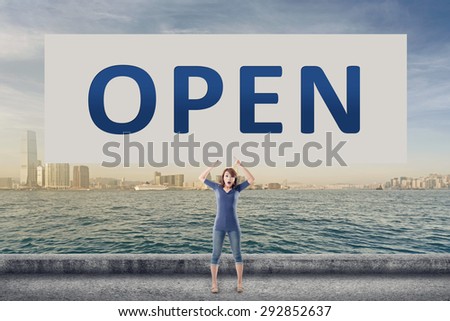 Open, words on blank board hold by a young girl in the outdoor.