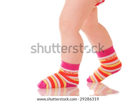 Baby legs in colorful socks walking on glass surface