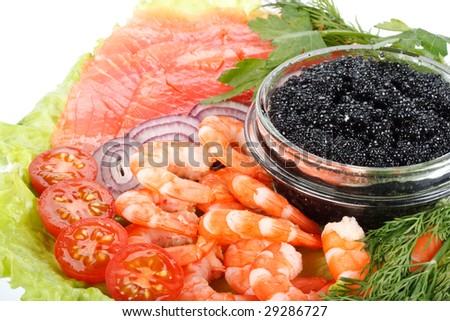 Black caviar, tiger shrimps and a salty trout with vegetables on a white background