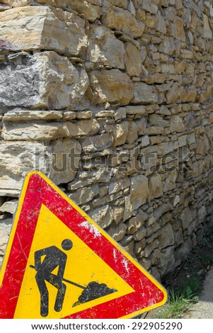 Road sign of work in progress against a wall in brick, rustic style.