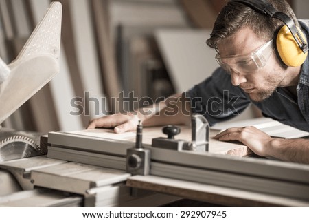 Young attractive man doing woodwork in carpentry Royalty-Free Stock Photo #292907945
