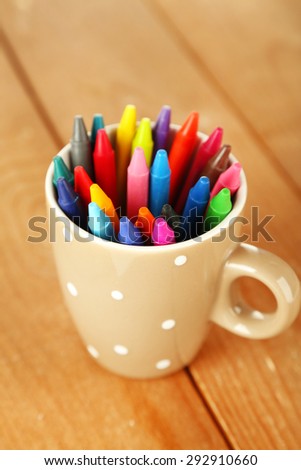 Colorful pastel crayons in cup on wooden background