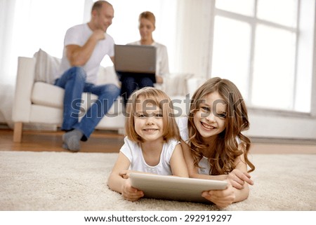 people, family, technology and children concept - happy little girls playing with tablet pc computer at home