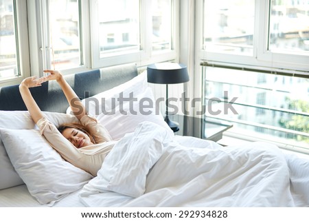 Woman stretching in bed after wake up Royalty-Free Stock Photo #292934828