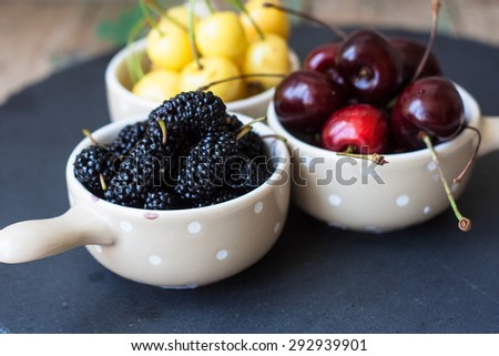 Fresh fruits in small bowls on a dark background