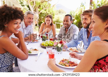 Friends dining together at a table in a garden Royalty-Free Stock Photo #292958423