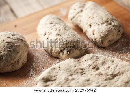 Close up of fresh bread dough with yeast and seeds on wooden plank  with flour. Shallow dof, selective focus