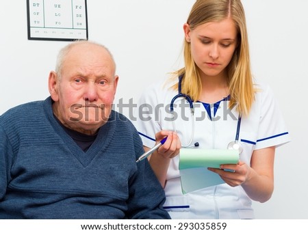 Young doctor writing prescription for sick elderly patient.