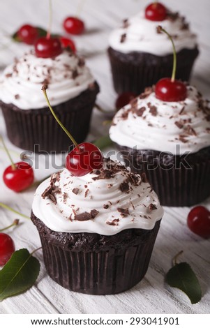 Chocolate cupcakes with white cream and cherry Black Forest close up on the table. vertical 