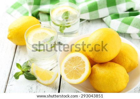 Fresh lemonade with lemon on white wooden background