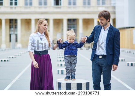 Happy family of three in the beautiful garden of Palais Royal in Paris