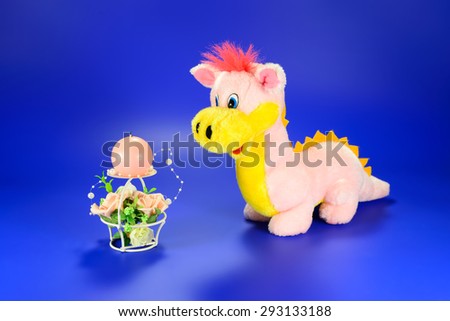 Pink dragon toy with decorative candle with flowers on a blue background
