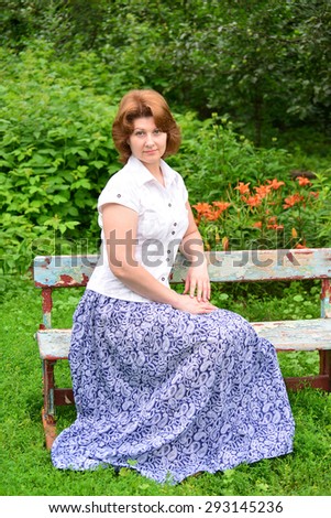 An adult woman sitting on a bench in the garden
