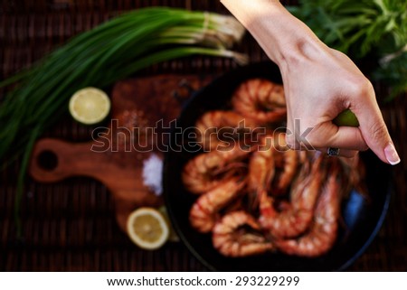 Waitress fish restaurant prepares to issue customers with prawns, fresh seafood are served with lime and green onion, Tiger shrimps fried on a grill in a deep cast iron skillet 