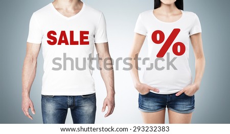 Close up of the bodies of man and woman in a white t-shirts with the red percentage sign and the word ' sale ' on the chest. Blue background.