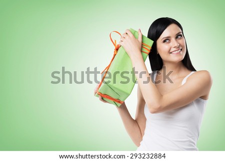 A brunette woman is holding a green gift box. Green background.