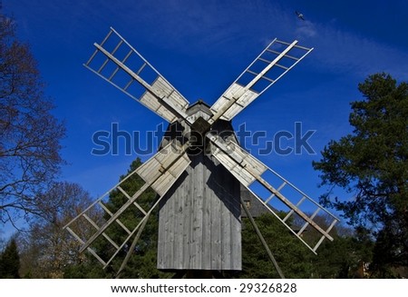 A photo of old wooden windmill in skansen