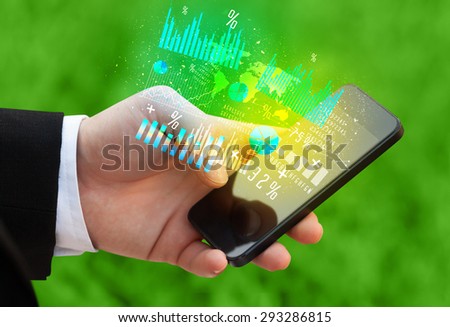 Hand holding smartphone with business diagrams on it
