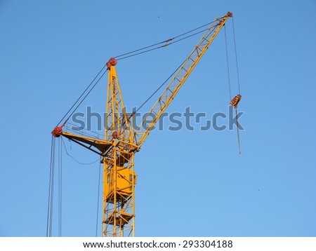 Yellow construction crane on a blue clear sky background