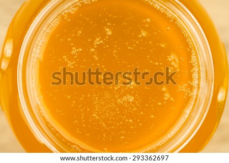 glass jar of fresh honey on wooden background, top view
