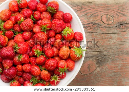 strawberries in white large plate on old wooden surface